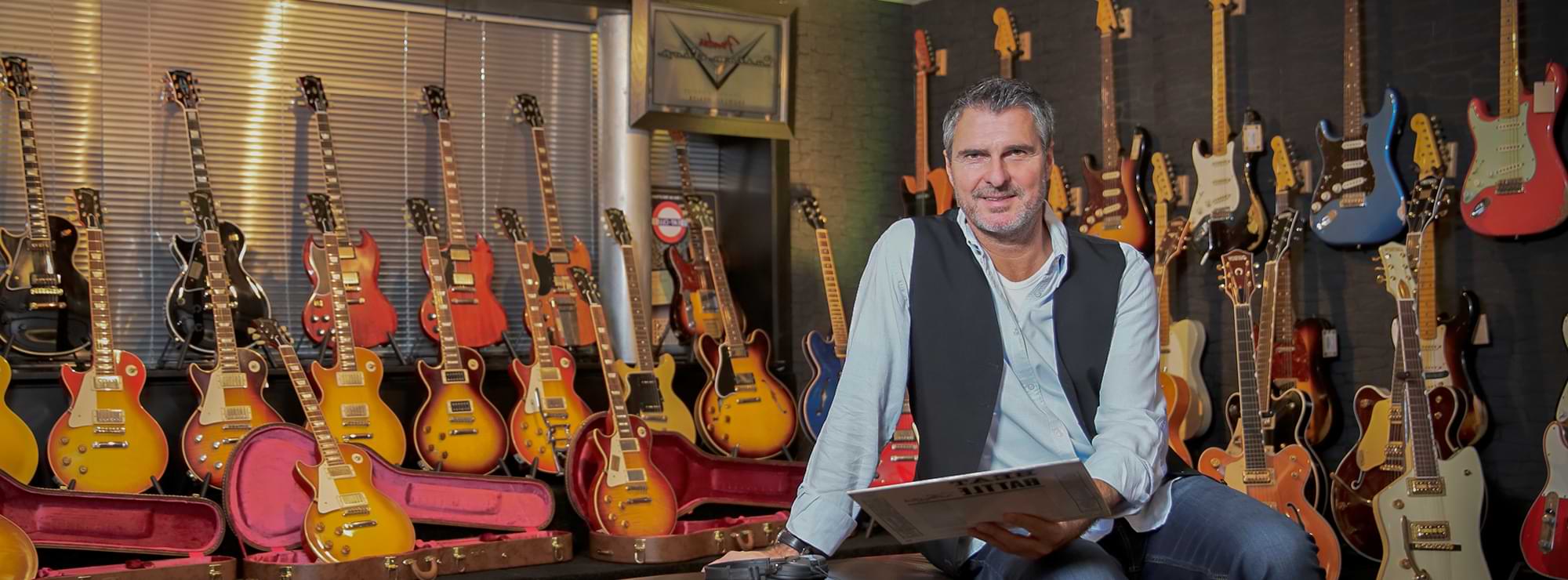 Uli Roth in einem Raum mit über 20 E-Gitarren, hält eine Schallplatte in der Hand Uli Roth in einem Raum mit über 20 E-Gitarren, hält eine Schallplatte in der Hand