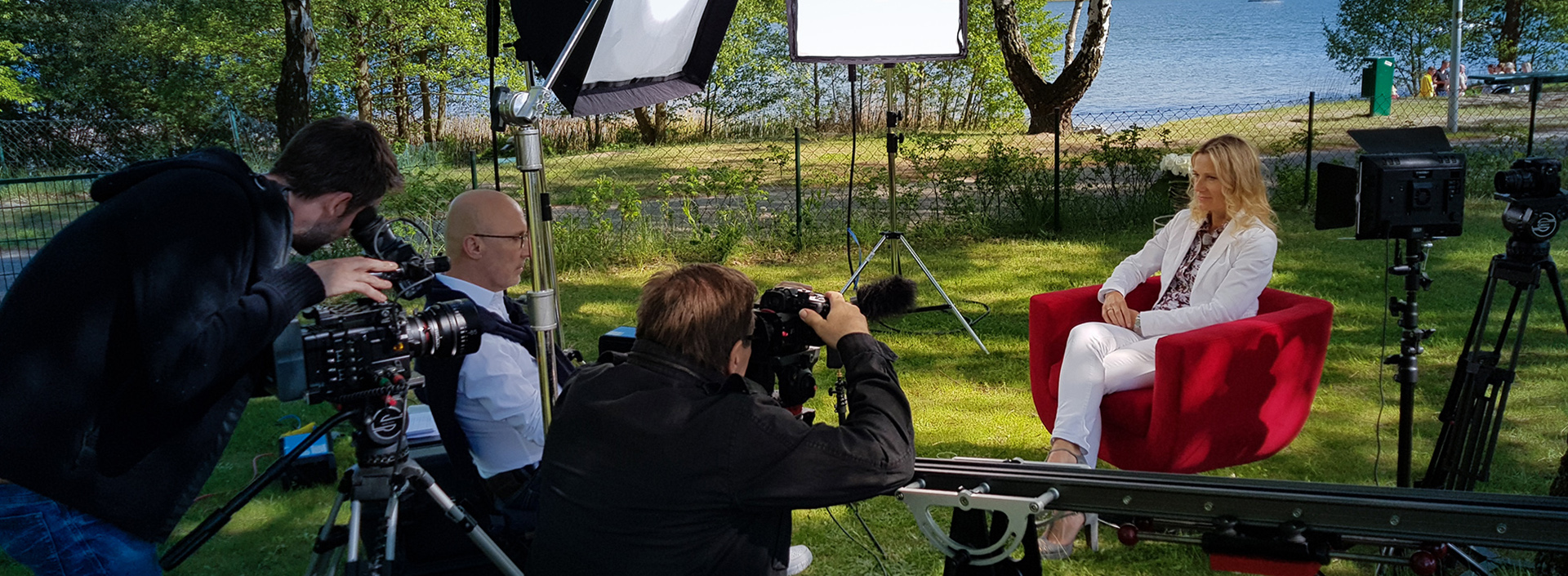 Sabrina Scherbarth sitzt auf einer grünen Wiese am See im Roten Sessel für ein Interview
