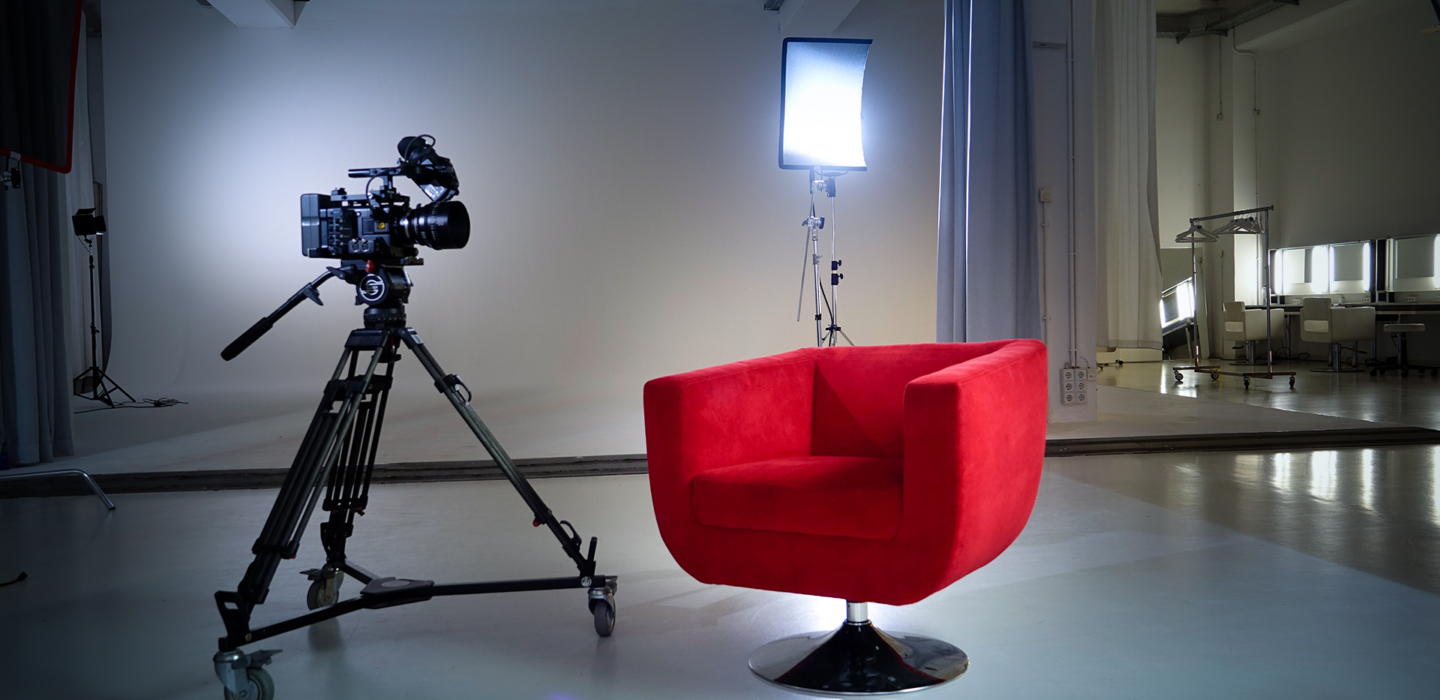 Der Rote Sessel und eine Kamera auf Stativ in einem Fotostudio-Set mit Lichtern