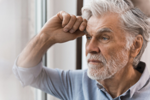 Mann in Gedanken lehnt an Fensterscheibe