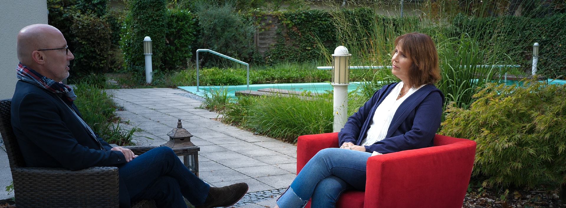 Monika Cramer sitzt in einer Grünanlage im Roten Sessel für ein Interview