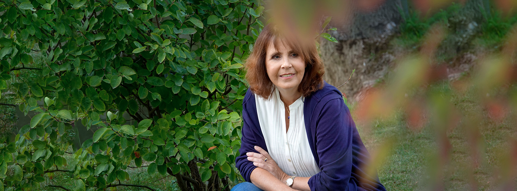 Monika Cramer kniet auf einer Wiese am Fluss