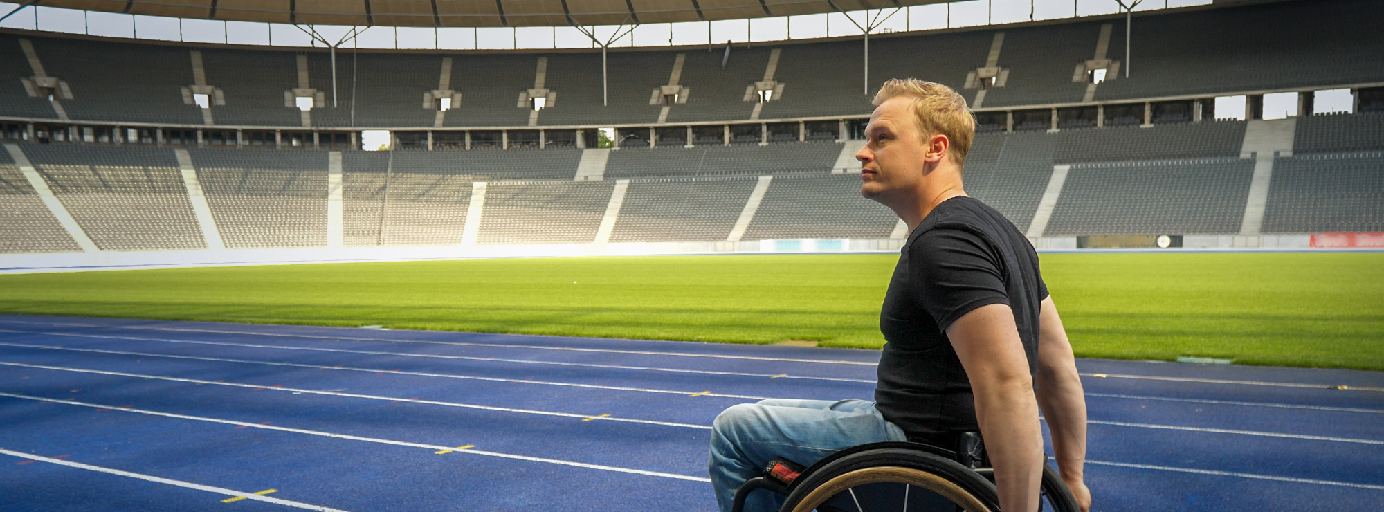 Benjamin Lenatz fährt mit seinem Rollstuhl über die blaue Laufbahn im Olympiastadion Berlin Benjamin Lenatz fährt mit seinem Rollstuhl über die blaue Laufbahn im Olympiastadion Berlin