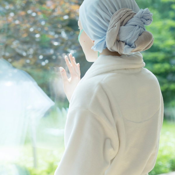 Eine krebskranke Frau berührt das Fenster im Hospiz während der Behandlung